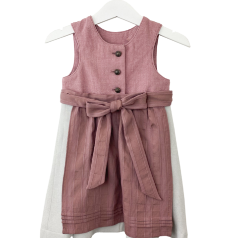 Babydirndl aus rosa-farbenen Leinenoberteil mit passepoilliertem Ausschnitt und 3 Knöpfe. Einfärbig beiger Rock mit Falten. Schürze ist einfärbig altrosa mit Bund und Bänder zum binden.